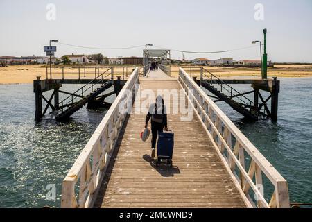 Ein Mann mit Taschen am Pier auf der Insel Culatra, Faro, Algarve, Portugal Stockfoto