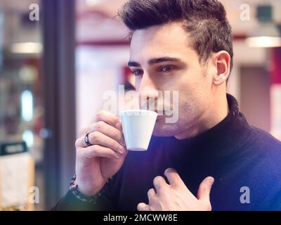 Mann trinkt Kaffee von außerhalb des Barfensters Stockfoto