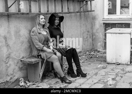 Schwarzweißfoto von zwei Freundinnen auf einer Bank im Garten. Eine der jungen Frauen hat schöne Haut und langes blondes Haar, die andere ist eine Stockfoto