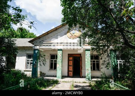 Ruinen einer verlassenen Schule in der Ukraine, zerbrochene Fenster und Türen in der Schule, altes und vergessenes Schulgebäude. Stockfoto