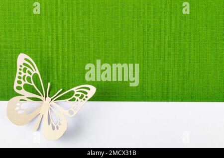 Schmetterling aus geschnitztem Papier oder Schnitt auf grünem und gelbem Hintergrund mit leerem Platz für Ihren Text oder Ihre Nachricht. Stockfoto