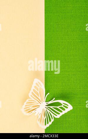 Schmetterling aus geschnitztem Papier oder Schnitt auf grünem und gelbem Hintergrund mit leerem Platz für Ihren Text oder Ihre Nachricht. Stockfoto