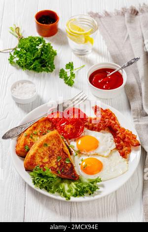 Kartoffelfarls, Spiegeleier, Rührei oder Speckscheiben, gegrillte Tomaten und frischer Salat auf weißem Teller auf weißem Holztisch, irisches Frühstück, vertikal Stockfoto