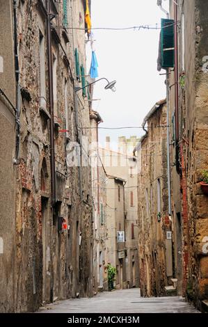 Mittelalterliche Straßenszene mit blau-weiß-gelber Waschung, die hoch hängt, Roccatederighi, mittelalterliche ummauerte Stadt, Toskana, Italien, Stockfoto