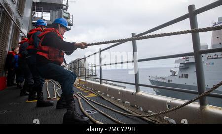 220712-N-XK047-1119 PAZIFIK (12. Juli 2022) – Seeleute legen beim Betanken auf See mit dem Amphibienschiff USS John P. Murtha (LPD 26) auf dem Cockpit des Amphibienschiffs USS Makin Island (LHD 8), Juli 12, eine Leine an. Makin Island ist in der Lage, andere Schiffe für humanitäre Hilfe oder zur Unterstützung anderer militärischer Mittel während einer Mission mit Treibstoff zu versorgen und zu versorgen. Makin Island führt derzeit Routineeinsätze in der US-3.-Flotte durch. Stockfoto