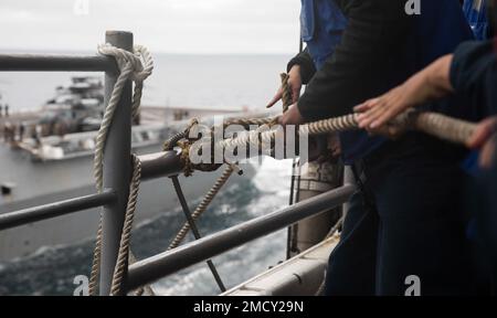 220712-N-XK047-1161 PAZIFIK (12. Juli 2022) – Matrosen sichern sich während eines Treibstoffes auf See mit dem Amphibienschiff USS John P. Murtha (LPD 26) auf dem Cockpit des Amphibienschiffs USS Makin Island (LHD 8), Juli 12. Makin Island ist in der Lage, andere Schiffe für humanitäre Hilfe oder zur Unterstützung anderer militärischer Mittel während einer Mission mit Treibstoff zu versorgen und zu versorgen. Makin Island führt derzeit Routineeinsätze in der US-3.-Flotte durch. Stockfoto