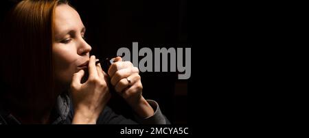 Frau raucht Marihuana, Cannabis durch ein Gerät auf schwarzem Hintergrund. Stockfoto