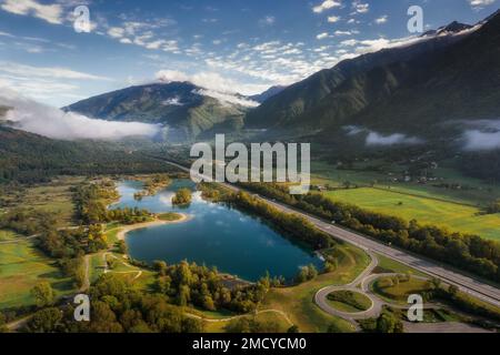 Naturlandschaften und Asphaltstraße entlang der Seen und Berge aus der Vogelperspektive Stockfoto