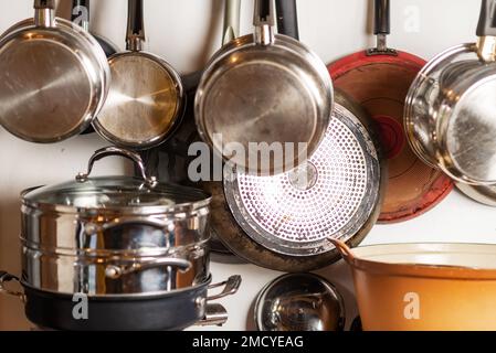 Töpfe und Pfannen hängen in der Küche. Küchenutensilien, Innenausstattung. Stockfoto