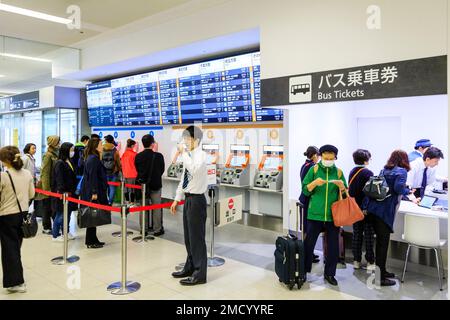 Tokio Haneda International Airport. Terminal 1 Interieur. Menschen mit einer Reihe von Bus Ticket Maschinen A und B, mit beleuchtetem Zeitplan vor. Stockfoto
