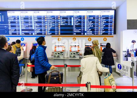 Tokio Haneda International Airport. Terminal 1 Interieur. Menschen mit einer Reihe von Bus Ticket Maschinen A und B, mit beleuchtetem Zeitplan vor. Stockfoto