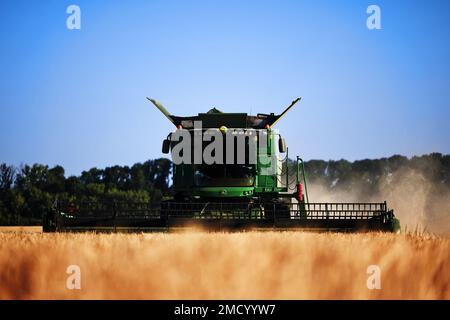 John Deere Erntemaschine arbeitet auf dem Feld. Mähdrescher Für Die Weizenernte. Getreidefeld während der Ernte. Moderne Ausrüstung funktioniert. 07.07.22, Rostow Stockfoto