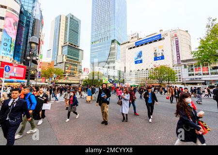 Tokio, Shibuya Wahrzeichen scramble Crossing. Massen von Menschen zu Fuß überqueren und direkt vor dem Bahnhof Shibuya auf Viewer. Straße. Stockfoto