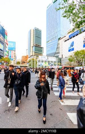 Tokio, Shibuya Wahrzeichen scramble Crossing. Massen von Menschen zu Fuß überqueren und direkt vor dem Bahnhof Shibuya auf Viewer. Straße. Stockfoto