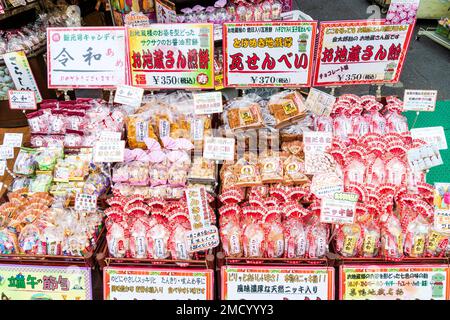 Tokio, Sugamo. Traditionelle japanische Süßigkeiten angezeigt außerhalb Sweet Shop. Bonbons und Süßigkeiten verpackt in Plastiktüten mit Rot und Gold twisted Tops. Stockfoto