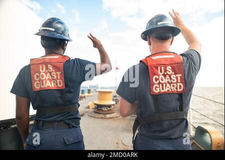 Zwei Küstenwachmänner an Bord der USCGC Bear (WMEC 901) erfüllen ihre Aufgaben als Mitglieder der Ankereinheit Atlantic Ocean, 11. Juli 2022. Die blauen Helme, die von beiden Männern getragen wurden, kennzeichnen sie als qualifizierte Besatzungsmitglieder für die Evolution. Stockfoto