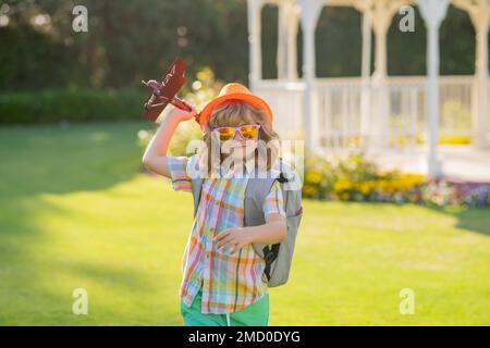 Kindheit auf dem Land. Fröhlicher Junge spielt draußen im Flugzeug. Das Konzept von Träumen und Reisen. Träume von Flugzeugen. Stockfoto