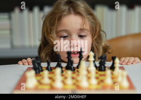 Kleines Kind spielt Schach. Kind spielt Brettspiel. Denk-Kind-Brainstorming und Idee im Schachspiel. Kinder Frühentwicklung. Ein Junge, der Schach spielt Stockfoto