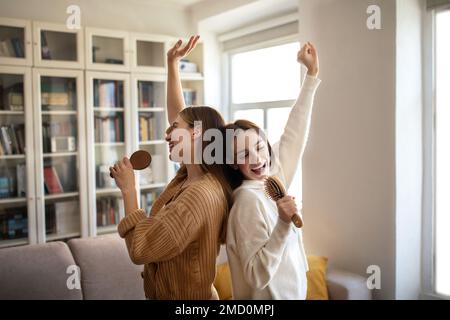 Fröhliche, aufgeregte europäische junge Superstar-Damen viel Spaß, singen Sie ein Lied am imaginären Mikrofon, genießen Sie Ihre Freizeit Stockfoto