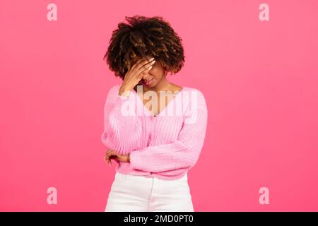 Verzweifelte traurige afroamerikanische lockige Frau, die ihr Gesicht zwanglos mit der Hand bedeckte und weinte Stockfoto