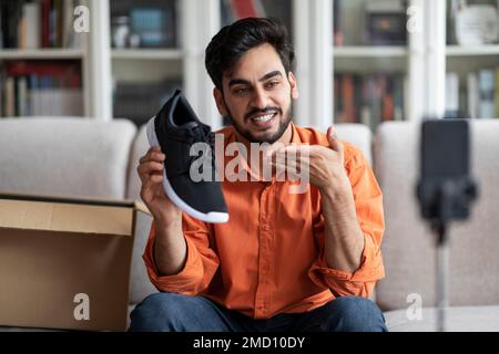 Attraktiver modeblogger für einen arabischen Typen, der brandneue Schuhe zeigt Stockfoto