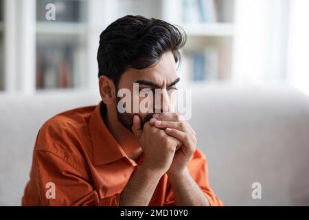 Nahaufnahme eines traurigen Mannes aus dem Nahen Osten, der zu Hause auf der Couch sitzt Stockfoto
