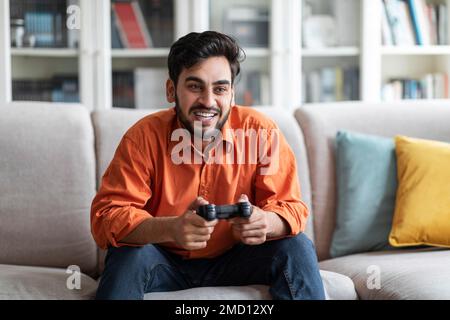 Ein hübscher junger Mann aus dem Nahen Osten, der zu Hause Videospiele spielt Stockfoto