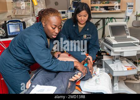 220712-N-VQ947-1108 PAZIFIK (12. Juli 2022) — Hospital Corpsman 2. Klasse Andrea Thomas, links, aus Pascagoula, Mississippi, Und Hospital Corpsman 3. Klasse Brittany Nguyen, rechts, aus Sioux City, Iowa, stabilisiert einen simulierten Patienten während einer medizinischen Evakuierungsübung an Bord eines Amphibienschiffs der San Antonio-Klasse USS Portland (LPD 27) während Rim of the Pacific (RIMPAC) 2022 in Südkalifornien. Von Juni 29 bis August 4 nehmen an der RIMPAC in und um den hawaiianischen Islan sechsundzwanzig Nationen, 38 Schiffe, vier U-Boote, mehr als 170 Flugzeuge und 25.000 Mitarbeiter Teil Stockfoto