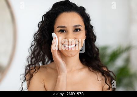 Portrait von glücklicher arabischer Millenial lockiger weiblicher Haut mit Wattepad, genießen Sie einen guten Morgen allein Stockfoto