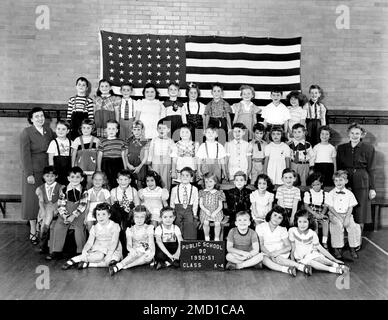 Ein Archivfoto eines Klassenzimmers von 1950er, in dem sich Schüler vor der amerikanischen Flagge 1950 befanden. Stockfoto