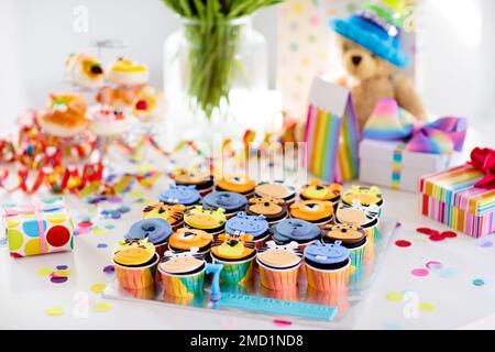 Cupcakes für Kinder Geburtstagsfeier. Kinderparty mit Dschungeltieren. Dekoriertes Zimmer für Jungen oder Mädchen Kindergeburtstage. Tischeinstellung mit Geschenken Stockfoto