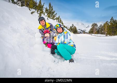 Familie, Mutter, Vater und Tochter bauen einen kleinen Schneemann neben der Skipiste. Skiurlaub im Winter in Andorra, El Tarter, Pyrenäen Stockfoto