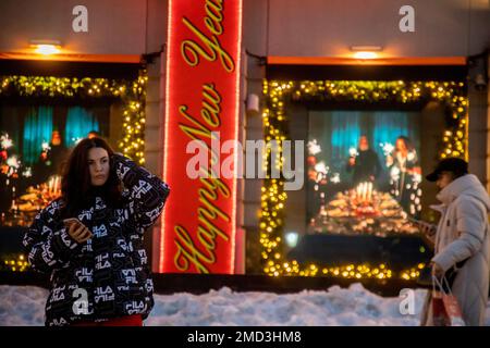 Moskau, Russland. 2. Januar 2023. Die Menschen gehen entlang der Fußgängerzone Kuznetsky vor dem Hintergrund der Schaufenster des TSUM Kaufhauses im Zentrum von Moskau, das für das neue Jahr eingerichtet wurde, Russland Stockfoto