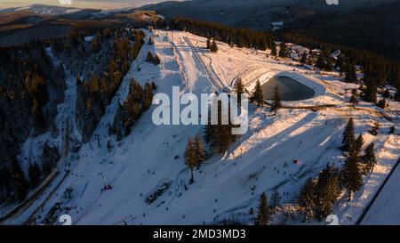 Luftaufnahme einer Skipiste auf dem Gipfel des Berges in der Wintersaison bei Sonnenuntergang. Die Fotografie wurde von einer Drohne aus einer höheren Höhe aufgenommen. Luftaufnahme o Stockfoto