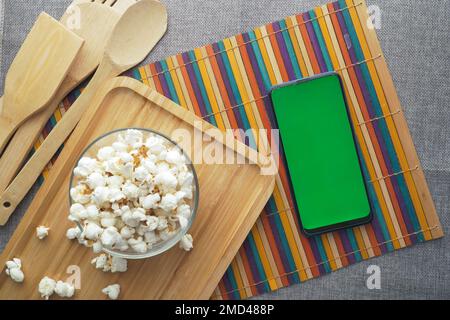Draufsicht auf Smartphone und Popcorn auf dem Tisch Stockfoto