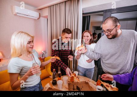 Freunde auf der Party. Die Leute essen Pizza und trinken Bier. Stockfoto