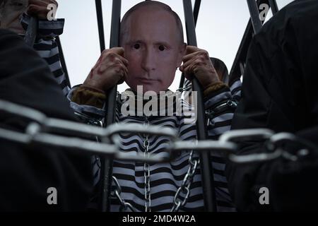 Ein Mann in GefängnisOverals mit einer Vladimir Putin Maske wird während einer Kundgebung vor der russischen Botschaft am ukrainischen Tag der Einheit in Warschau, Polen, am 22. Januar 2023 gesehen. Demonstranten fordern die Schaffung eines Internationalen Kriegsverbrechertribunals, um russische Kriegsverbrechen vor Gericht zu bringen. Während der Kundgebung wurden vier Männer in GefängnisOveralls mit Gesichtsmasken von Wladimir Putin, dem russischen Verteidigungsminister Serge Shoigu, dem russischen Außenminister Sergej Lawrow und dem belarussischen Präsidenten Aleksander Lukaschenko zu einem Scheinprozess in einem Käfig gebracht, der für Kriegsverbrechen verurteilt wurde. (Pho Stockfoto