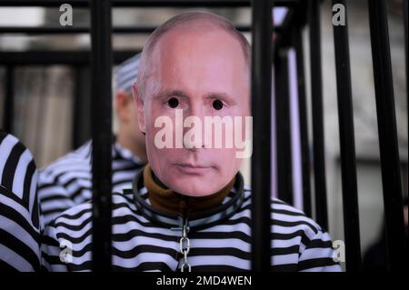 Ein Mann in GefängnisOverals mit einer Vladimir Putin Maske wird während einer Kundgebung vor der russischen Botschaft am ukrainischen Tag der Einheit in Warschau, Polen, am 22. Januar 2023 gesehen. Demonstranten fordern die Schaffung eines Internationalen Kriegsverbrechertribunals, um russische Kriegsverbrechen vor Gericht zu bringen. Während der Kundgebung wurden vier Männer in GefängnisOveralls mit Gesichtsmasken von Wladimir Putin, dem russischen Verteidigungsminister Serge Shoigu, dem russischen Außenminister Sergej Lawrow und dem belarussischen Präsidenten Aleksander Lukaschenko zu einem Scheinprozess in einem Käfig gebracht, der für Kriegsverbrechen verurteilt wurde. (Pho Stockfoto