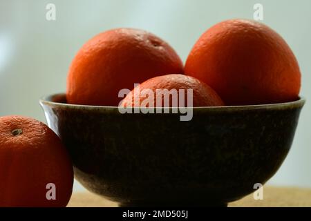 Nahaufnahme frischer und saftiger heller orangefarbener Mandarinen auf dunklem Hintergrund; geringe Schärfentiefe Stockfoto