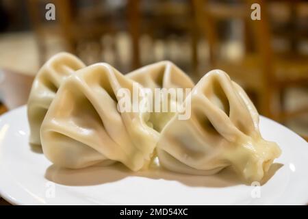 Khinkali gefüllt mit Hackfleisch auf weißem Teller. Nahaufnahme der traditionellen Teigtaschen in Tiflis, Georgia. Nationale georgische Küche Stockfoto