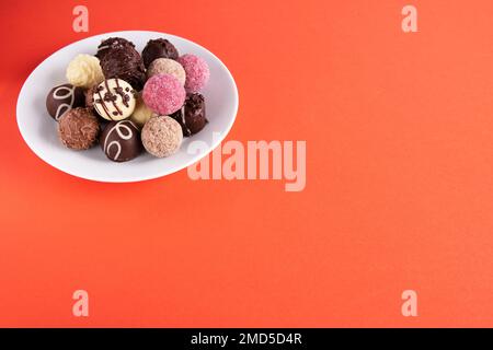 Fotoschokoladenbonbons auf einem runden Teller auf einem farbigen Hintergrund Stockfoto