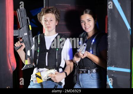 Porträt von Frau und Mann, die eine Laserpistole in der Arena halten und Laser-Tag-Spiel mit Freunden spielen Stockfoto