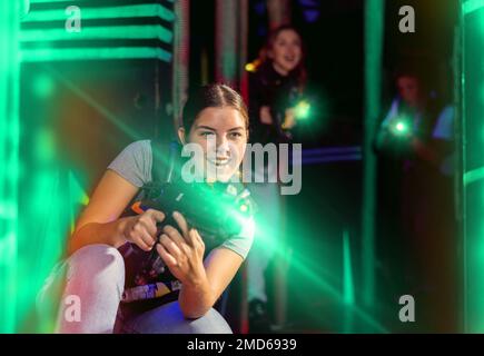 Mädchen läuft und weicht aus, während sie Lasertag spielt Stockfoto