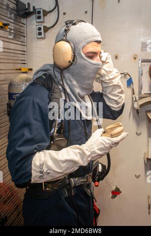 USA Navy Airman Pedro Olague aus Los Angeles, dem Flugzeugträger USS John C. Stennis (CVN 74) zugeteilt, betreibt während einer Übung zur Schadensbegrenzung an Bord des Schiffes am 13. Juli 2022 in Newport News, Virginia, ein schallbetriebenes Telefon. John C. Stennis arbeitet in Newport News Shipyard zusammen mit NNS, NAVSEA und Auftragnehmern, die im Rahmen der Mission, das Kriegsschiff rechtzeitig und im Rahmen des Budgets wieder in den Kampf zurückzubringen, ihre Pflicht zur Verteidigung der Vereinigten Staaten wiederaufnehmen. Stockfoto