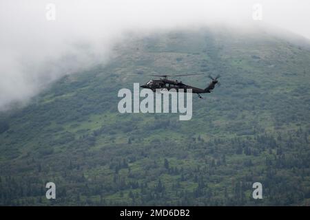 Ein Alaska Army National Guard UH-60L Black Hawk, der von einer dem 1. Bataillon, dem 207. Truppenkommando der Luftfahrt, zugeteilten Besatzung betrieben wird, transportiert Anchorage Police Department Special Weapons and Tactics (SWAT) Team Officers über Joint Base Elmendorf-Richardson, Alaska, 13. Juli 2022. Die ausgedehnten und strengen Ausbildungsbereiche von JBER boten den idealen Rahmen für örtliche Einsatzteams der Strafverfolgungsbehörden, da sie ihre Fähigkeiten im ländlichen Bereich, Aufgabenplanung, Aufklärung, Sicherheitsverfahren für Hubschrauber, Landnavigation, Team-Bewegung und Patrouille. Stockfoto