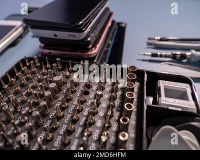 Altes defektes Smartphone und Reparaturwerkzeug. Das Konzept der Computerausrüstung, Mobiltelefone, Elektronik, Reparatur, Modernisierung und Technologie. Nahaufnahme. Stockfoto