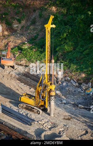 Der gelbe Pfahltreiber steuert die Fundamentpfähle auf der Baustelle. Stockfoto