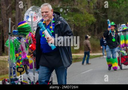 Bei der Mardi Gras-Parade auf Dauphin Island, Alabama, verkaufen Straßenverkäufer Blasengewehre und andere Schmuckstücke. Stockfoto