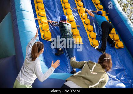 Freunde klettern auf aufblasbare Rutsche im Vergnügungspark Stockfoto