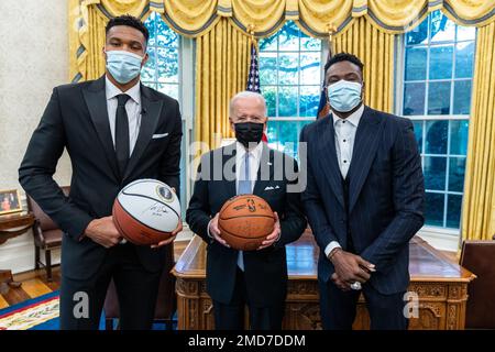 Reportage: President Joe Biden unterzeichnet einen Basketball und nimmt eine Videonachricht mit Giannis Antetokounmpo und Thanasis Antetokounmpo vom 2021. NBA-Champion Milwaukee Bucks auf, Montag, den 8. November 2021, im Oval Office Stockfoto